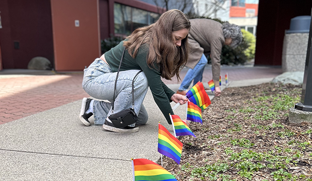 Girl placing a pride flag in the ground.