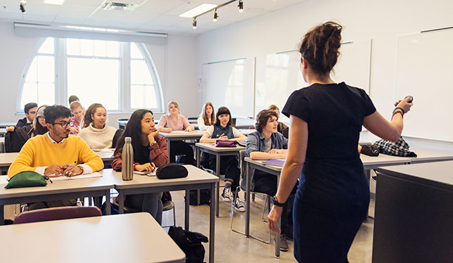 A classroom full of students fronted by a female teacher.