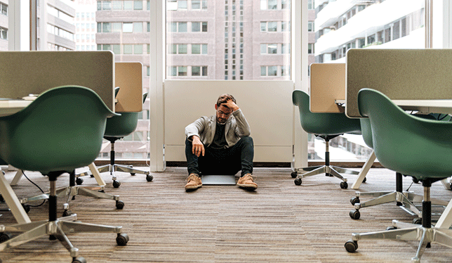 A frustrated man sitting on the floor.