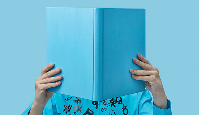 Person in blue hiding behind a book.