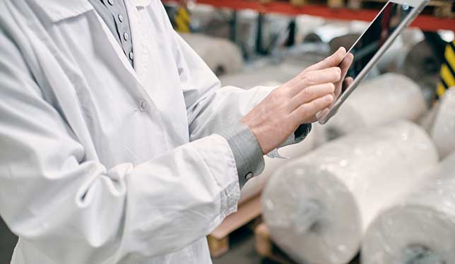 A scientist using an ipad while setting up a lab