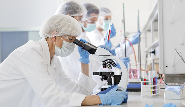 Scientists in protective suits in a science laboratory study a virus