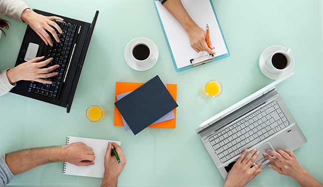 Four pairs of hands with laptops