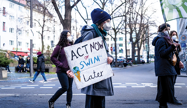 Protestors with a sign that says Act Now or Swim Later.