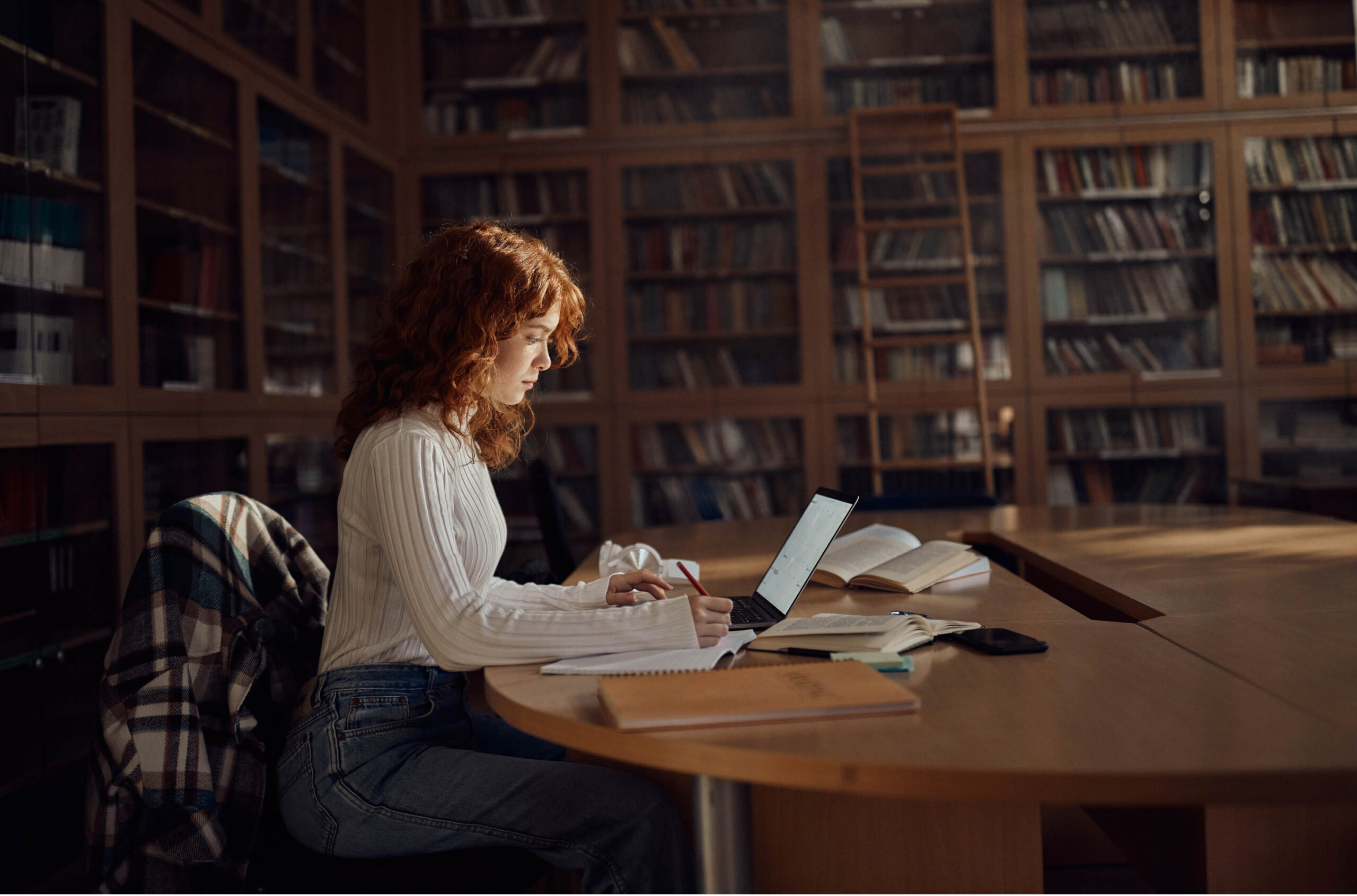 Woman sitting in library working on a laptop